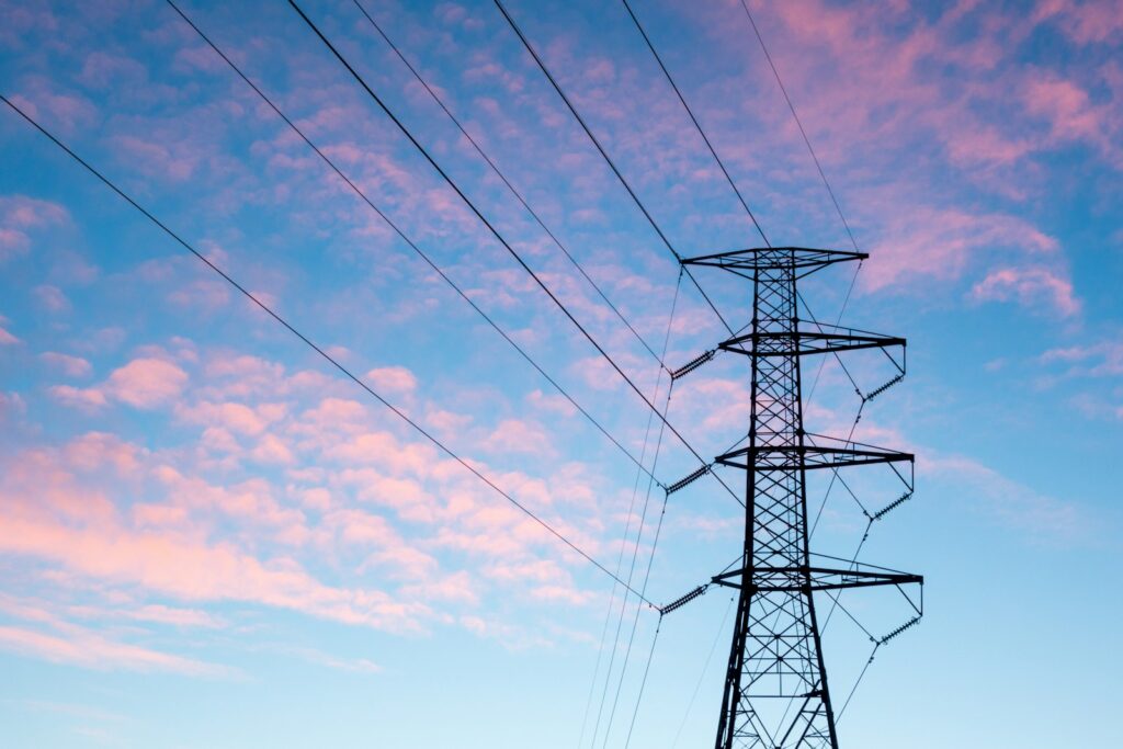 Pylône électrique haute tension sous un ciel de nuages orangés