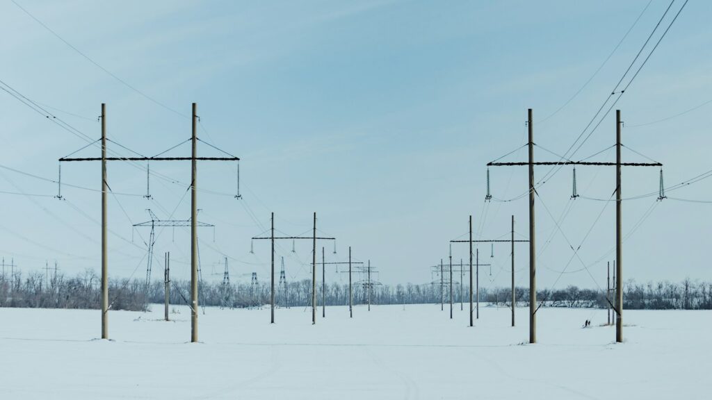 Lignes électriques à haute tension traversant un champ enneigé en hiver